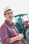 Close up of senior farmer wearing hat while standing against tractor in field