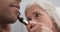 Close up of senior female medical doctor using otoscope to examine patients ear