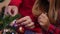 Close-up senior male hand hanging New Year toy on Christmas tree and teenage female palm touching decoration