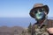 Close-up of senior man in surgical mask traveling in mountain landscape in Tenerife, horizon over the sea - new normal life