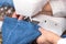 Close-up of senior woman hands seamstress sewing jeans on electrical sewing machine.