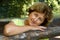 Close up of serene and smiling senior woman in the bench in the park, blurred background