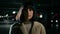 Close up serious calm Caucasian woman standing at empty dark dangerous parking lot looking down look at camera. Portrait