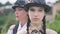 Close-up serious face of young slim beautiful Caucasian woman in steampunk outfit posing outdoors with blurred adult