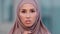 Close-up serious female face portrait outdoors young muslim islamic woman in hijab stands on street looking at camera