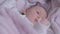 Close-up serious newborn Caucasian girl with big grey eyes looking away moving hands. Portrait of infant lying in soft