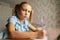 Close-up of serious primary little child girl writing doing homework sitting at home table by window, looking at camera.