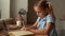 Close-up of serious smart Caucasian preschool school girl pupil studying at home sitting at desk by window.