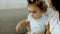 Close-up of serious toddler sitting with her mom on sofa.