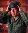 Close up of a serious veteran soldier wearing a helmet and a military uniform, with both hands adjusting the helmet, in