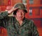 Close up of a serious veteran soldier wearing a helmet and a military uniform, doing a sign of greetings to the