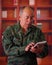 Close up of a serious veteran soldier wearing a helmet and a military uniform, using his tablet in a blurred background