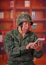 Close up of a serious veteran soldier wearing a helmet and a military uniform, using his tablet in a blurred background