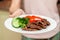 Close-up serving homemade grilled beef medallions with grilled pepper, fresh cucumber and parsley on a round white plate. Concept