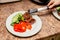 Close-up serving homemade grilled beef medallions with grilled pepper, fresh cucumber and parsley on a round white plate. Concept