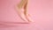 Close up of shapely female legs while running in sneakers on coral background