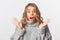 Close-up of shocked gasping girl in grey sweater, open mouth amazed, standing over white background