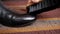 Close-up of a shoe brush rubs a black leather boot