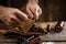 Close up of a shoemaker or artisan worker hands. Leather craft tools on old wood table. Leather craft workshop