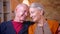 Close-up shoot of senior caucasian couple sit together at sofa watching tenderly at each other at home.