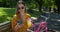 Close-up shooting. Portrait of attractive young woman with a bicycle used smartphone and drinking lemonade on a park