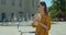 Close-up shooting. Young woman on a bicycle drinking lemonade on the square in front of the fountain. Fashionable young