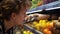 Close-up of shop assistants in transparent gloves filling up lemons storage stands with assorted organic groceries in