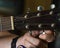 Close-up shot of an acoustic guitar fretboard with male fingers tuning the guitar