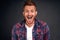 Close-up shot of amazed and joyful adult redhead male model with beard smiling broadly with dropped jaw and impressed expression,