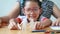 Close up shot Asian little girl in Thai kindergarten student uniform and her mother playing cut of white paper making family shape