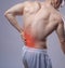 Close up shot. Athletic muscular man has pain in the back. Red spot of backache