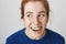 Close-up shot of attractive young caucasian female with red hair and freckles laughing and looking aside, being in