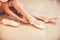 Close-up shot of a ballerina taking off the ballet shoes sitting on the floor in the studio