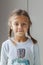 Close up shot of beautiful Ñaucasian little girl with pigtails wearing cozy sweater, looking at camera with charming smile,