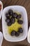 Close-up shot of black olives in oil filled white plate