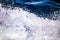 A close up shot of the blue waters of a rough sea with splashes, foam and waves