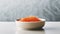 A close-up shot of a bowl filled with vibrant red trout caviar placed elegantly on a sleek concrete table in a modern