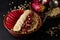 Close up shot of a bowl with oat porridge, banana, pomegranate seeds and opuntia cactus fruit on black background