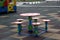Close-up shot of bright colorful new round child small plastic table and five stools outdoors on square rubber flooring on kinderg