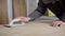 Close up shot of a builder sanding a piece of hard wood in a workshop.