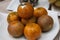 Close-up shot of the bunch of oranges on the white ceramic plate.