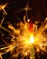 Close-up shot of a burning sparkling bright firework stick in the darkness