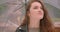 Close-up shot of caucasian brunette model opens umbrella predicting the rain in the green rainy park.