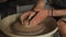 Close-up shot of ceramic cup spinning on potters\'s wheel and hands molding clay