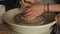 Close-up shot of ceramic cup spinning on potters\\\'s wheel and hands molding clay