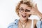 Close-up shot of charismatic happy and enthusiastic stylish young emotive woman with blond short haircut in glasses and