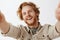 Close-up shot of charming friendly and carefree happy redhead guy with stylish wavy hairstyle and beard tilting from joy