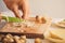 Close-up shot of chef`s hand who is cutting mushrooms with other ingredients on wooden cut board