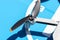 A close-up shot of the complex propellers and brushless motor of a drone against the backdrop of a blue landing pad.