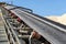 Close-up shot of the conveyor belt in the concrete plant with transport rollers, visible metal stairs and railings.